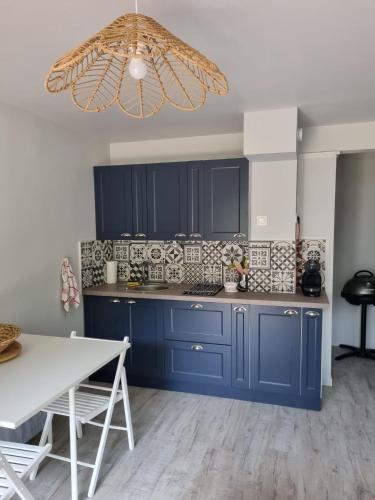 une cuisine avec des armoires bleues et une table blanche dans l'établissement Appartement VILLERS SUR MER, à Villers-sur-Mer