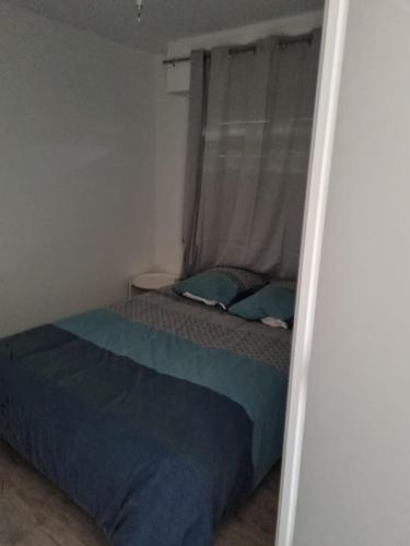 - une chambre avec un lit et une fenêtre avec une couverture bleue dans l'établissement Appartement VILLERS SUR MER, à Villers-sur-Mer
