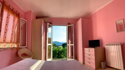 ein Schlafzimmer mit rosa Wänden und einem großen Fenster in der Unterkunft Ligo in Villanova dʼAlbenga