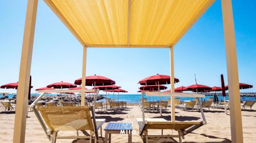 a beach with chairs and umbrellas and the ocean at MIIO HOTEL in San Vincenzo