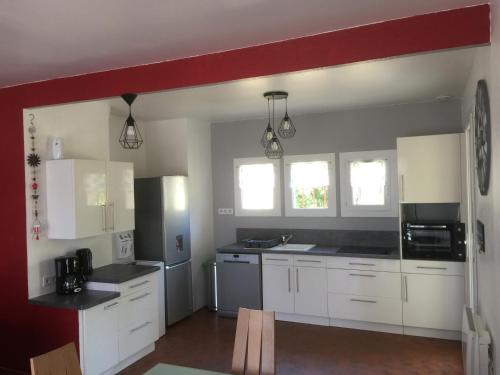 une cuisine avec des placards blancs et un mur rouge dans l'établissement La Perline, Maison individuelle - 4 à 6 personnes, à Le Crestet
