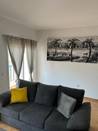 a living room with a black couch with yellow pillows at Daisal Apartment - 2 bedroom apartment with balcony near the beach & city center, perfect for nomads, travellers, families, watersports! in Santa Maria