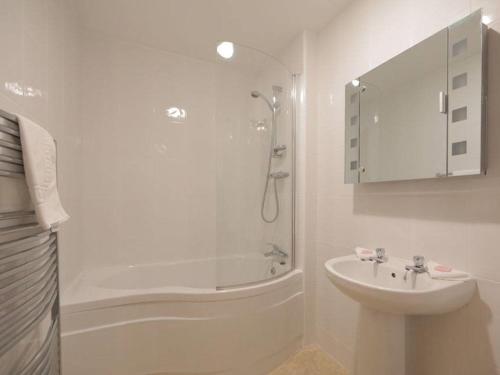 a white bathroom with a shower and a sink at St Magnus Bay Hotel in Hillswick