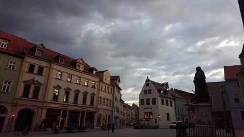 una calle de la ciudad con edificios y un cielo nublado en "goethezimmer" an der Herderkirche, en Weimar