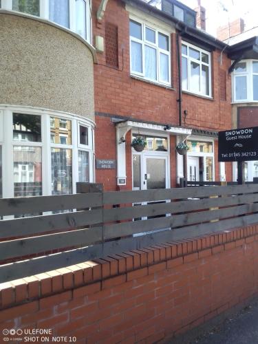 a wooden bench in front of a brick building at Snowdon House Single rooms for solo travellers in Rhyl