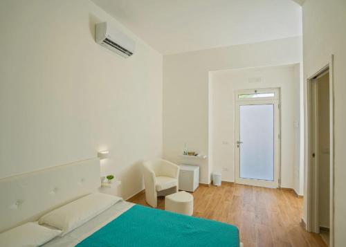 a white bedroom with a bed and a chair at Sea Dream in Agropoli