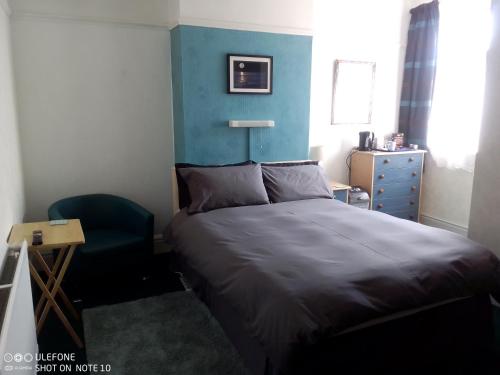 a small bedroom with a bed and a chair at Snowdon House Single rooms for solo travellers in Rhyl