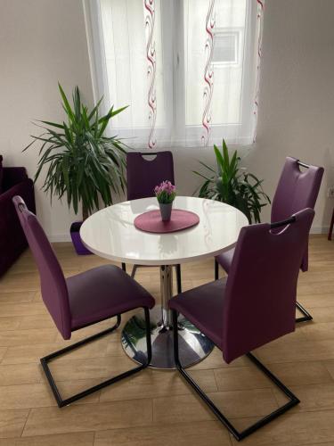 a white table and purple chairs in a room at Apartmani Marojević, Bar in Bar
