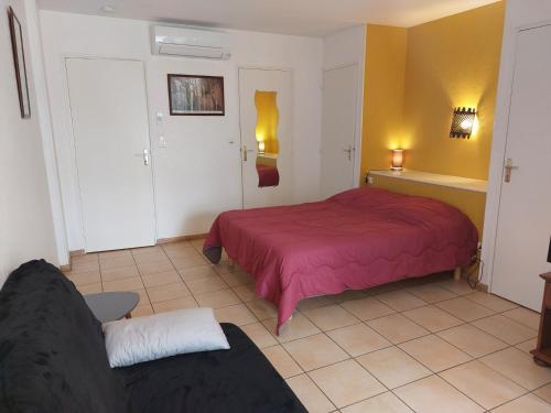 - une chambre avec un lit rouge et un canapé dans l'établissement GITE LE PARC A SARLAT Parking privé, à Sarlat-la-Canéda