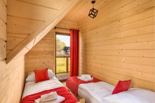 two beds in a log cabin with a window at Korona Gór in Białka Tatrzanska
