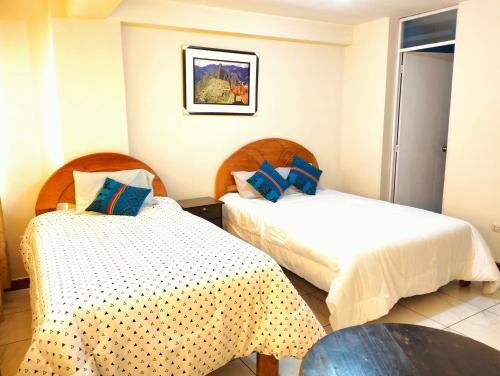 een hotelkamer met 2 bedden en een tafel bij Hostal Ukumari Andino in Cuzco