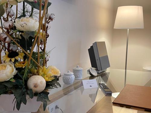 a desk with a computer monitor and flowers on it at Hotel Torremangana in Cuenca