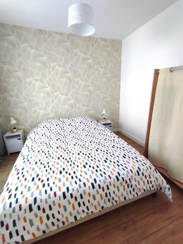 a bedroom with a bed with a polka dot bedspread at Les Nuits Bonneuilloises Le Percheron in Breteuil