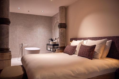 a bedroom with a large white bed with pillows at Heavens Hotel in Hoorn