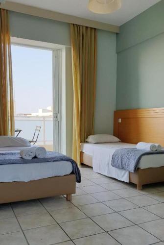 a bedroom with two beds and a large window at Yms studios in Rethymno Town