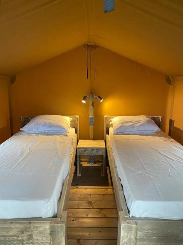 two twin beds in a room with a wall at Camping Miramar Playa - camas individuales in Torredembarra
