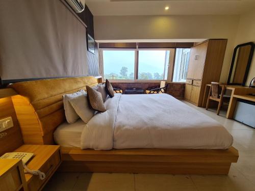 a bedroom with a large bed with a large window at Hotel Rajpur Heights in Dehradun
