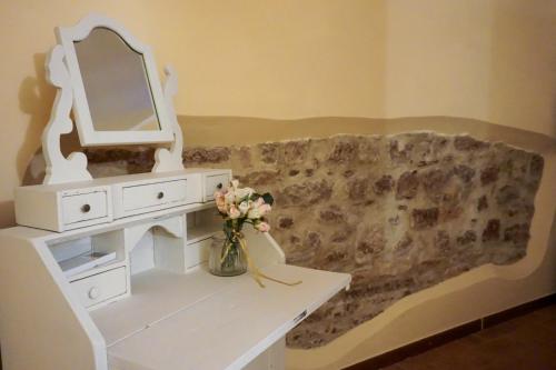 a white dressing table with a mirror and a vase with flowers at Nel vicolo dei Baci - Casa vacanze al Bacio in Spello