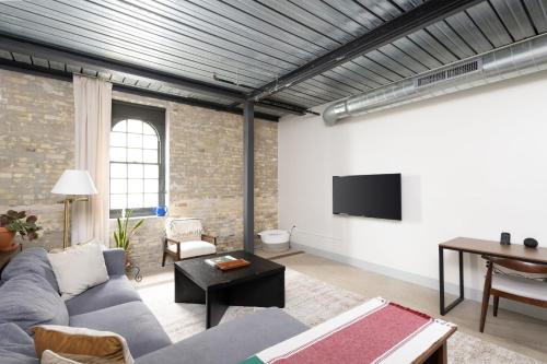 a living room with a couch and a table and a tv at Brewery District Luxe 2BR Near Fiserv with Parking in Milwaukee