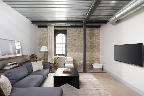 a living room with a couch and a flat screen tv at Brewery District Luxe 2BR Near Fiserv with Parking in Milwaukee