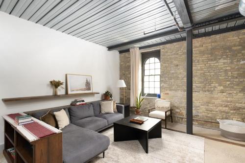 a living room with a couch and a brick wall at Brewery District Luxe 2BR Near Fiserv with Parking in Milwaukee