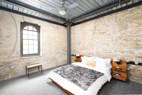 1 dormitorio con 1 cama grande y pared de ladrillo en Flexhome Brewery District 2BR Apt M11 - READ INFO, en Milwaukee