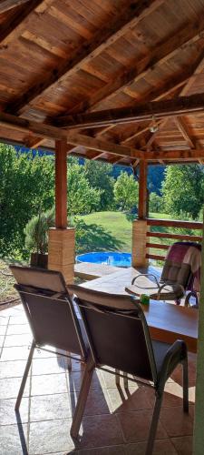 a patio with a table and chairs under a wooden roof at Private place, Boca in Bihać