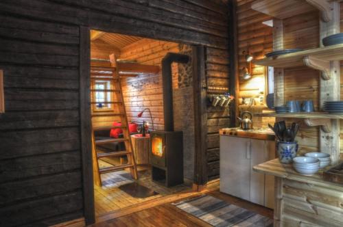 a kitchen in a log cabin with a stove at Cottage On Wild River In Lapland/Sweden in Karlsten