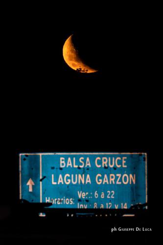a crescent moon flying over a sign with a billboard at La Balsa in José Ignacio