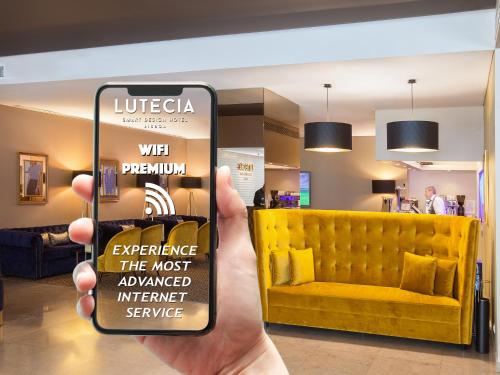 eine Hand, die ein Handy mit einer gelben Couch hält. in der Unterkunft Lutecia Smart Design Hotel in Lissabon