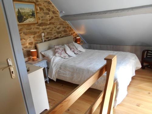 une chambre avec un lit et un mur en pierre dans l'établissement Les Landes Gîte, à Saint-Pardoux-Corbier