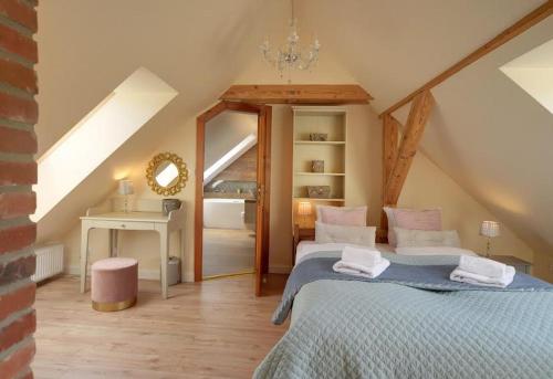 a attic room with a bed and a table and a mirror at Trevilles Art-Deco Józefina in Szklarska Poręba