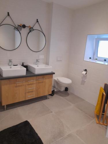 a bathroom with two sinks and a toilet and two mirrors at Aux champs Pressinois in Pressins