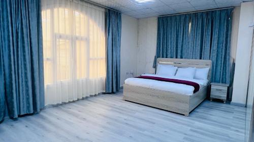 1 dormitorio con 1 cama con cortinas azules y ventana en Evan إيفان en Salalah