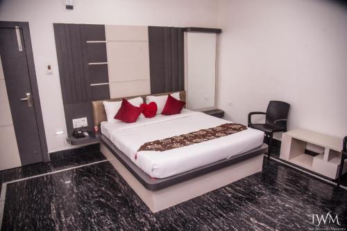 a bedroom with a large white bed with red pillows at Hotel La Vista Inn in Tinsukia