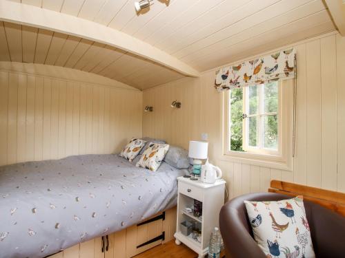 a small bedroom with a bed and a window at Shepherd's Hut at Retreat in Llanrhaeadr-ym-Mochnant