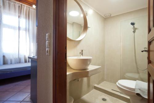 une salle de bain avec un lavabo, des toilettes et un miroir dans l'établissement Kalyvion Apartments, à Arachova