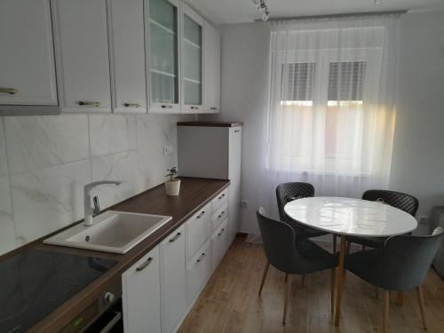 a kitchen with a sink and a table with chairs at Apartmani Sunlight in Vrnjačka Banja