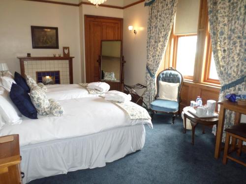 a bedroom with a large white bed and a chair at Camfield House in Thurso