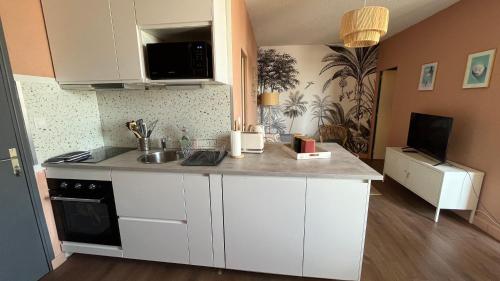 a kitchen with white cabinets and a counter top at Le Vichy Centre, spacieux et cosy T2 avec vue, au calme in Vichy