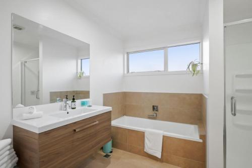 Baño blanco con bañera y lavamanos en Lux Modern 3BR Family House -Fenced Yard - Big TV en Auckland