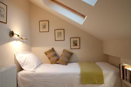 um quarto com uma cama com lençóis brancos e almofadas em Hay Retreats em Hay-on-Wye