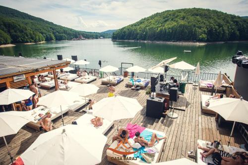 a dock with chairs and umbrellas on a lake at Franzdorf Alpin in Văliug