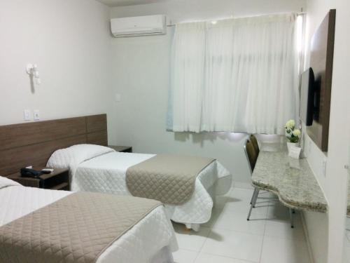 Habitación de hotel con 2 camas y escritorio en Itabuna Palace Hotel, en Itabuna