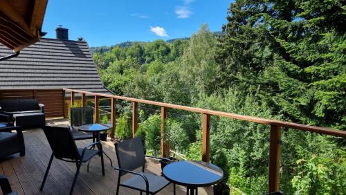 einen Balkon mit Tischen und Stühlen und Blick auf die Bäume in der Unterkunft Rezydencja Barrettski in Wisła