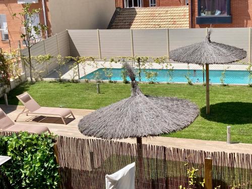馬德里的住宿－Moderno apartamento inteligente，一个带两把遮阳伞和一把椅子的庭院和一个游泳池