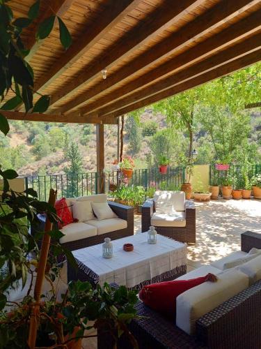 eine Außenterrasse mit Sofas, einem Tisch und Stühlen in der Unterkunft Glykoharama Cottage in Kalopanagiotis