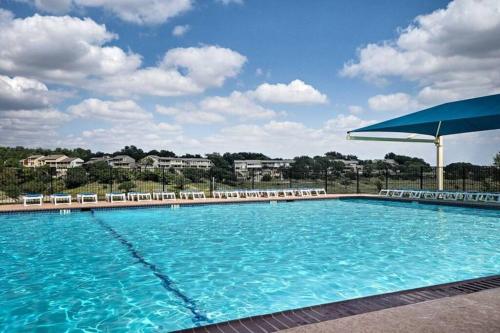 a large swimming pool with chairs and an umbrella at Cozy 3br/2bath vacation house at Lake Travis in Lago Vista