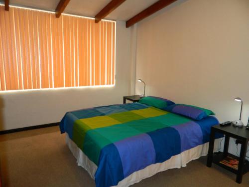 基多的住宿－ItsaHome Apartments - Torre Santos，一间卧室配有一张色彩缤纷的床和一扇窗户