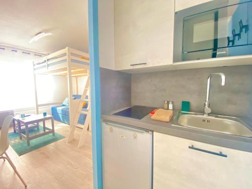 a kitchen with a sink and a room with a bunk bed at Le Lagon à 2 min du Futuroscope in Jaunay-Clan